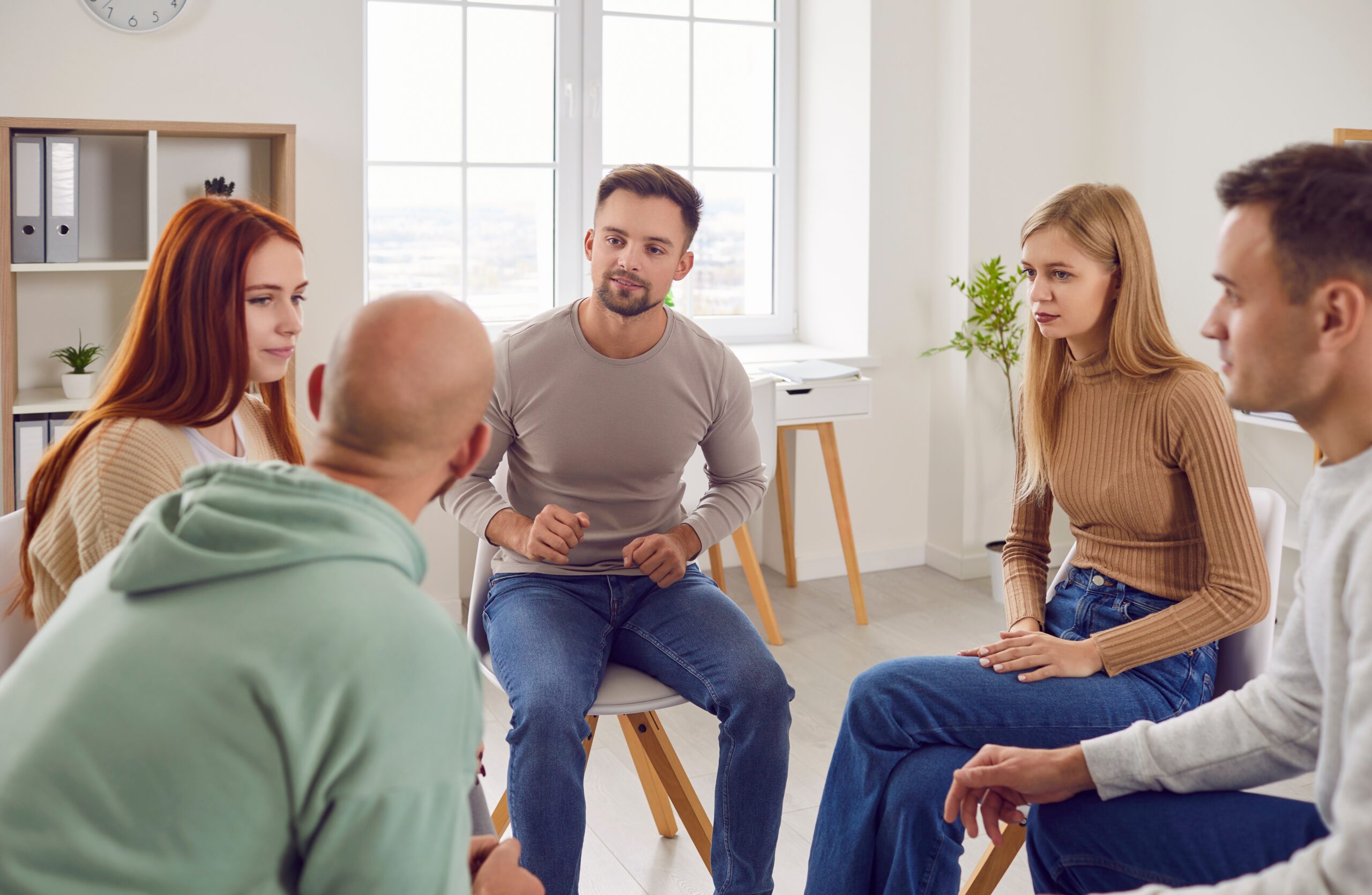 Group of men and women sitting in DBT group therapy.