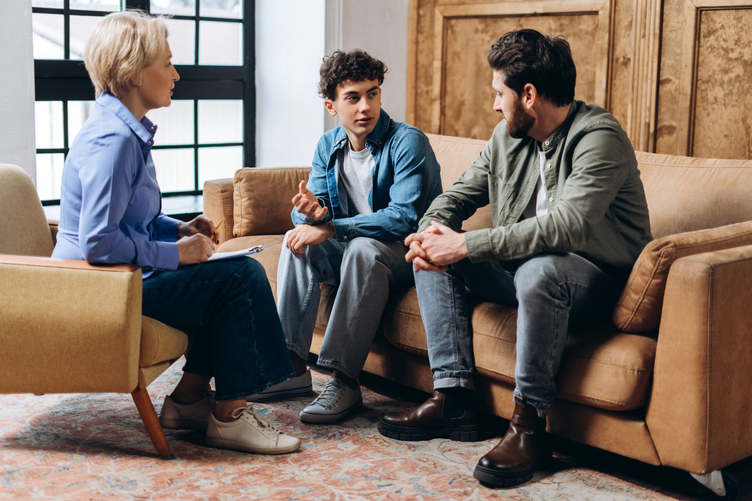 Female therapist talking to a man and his son.