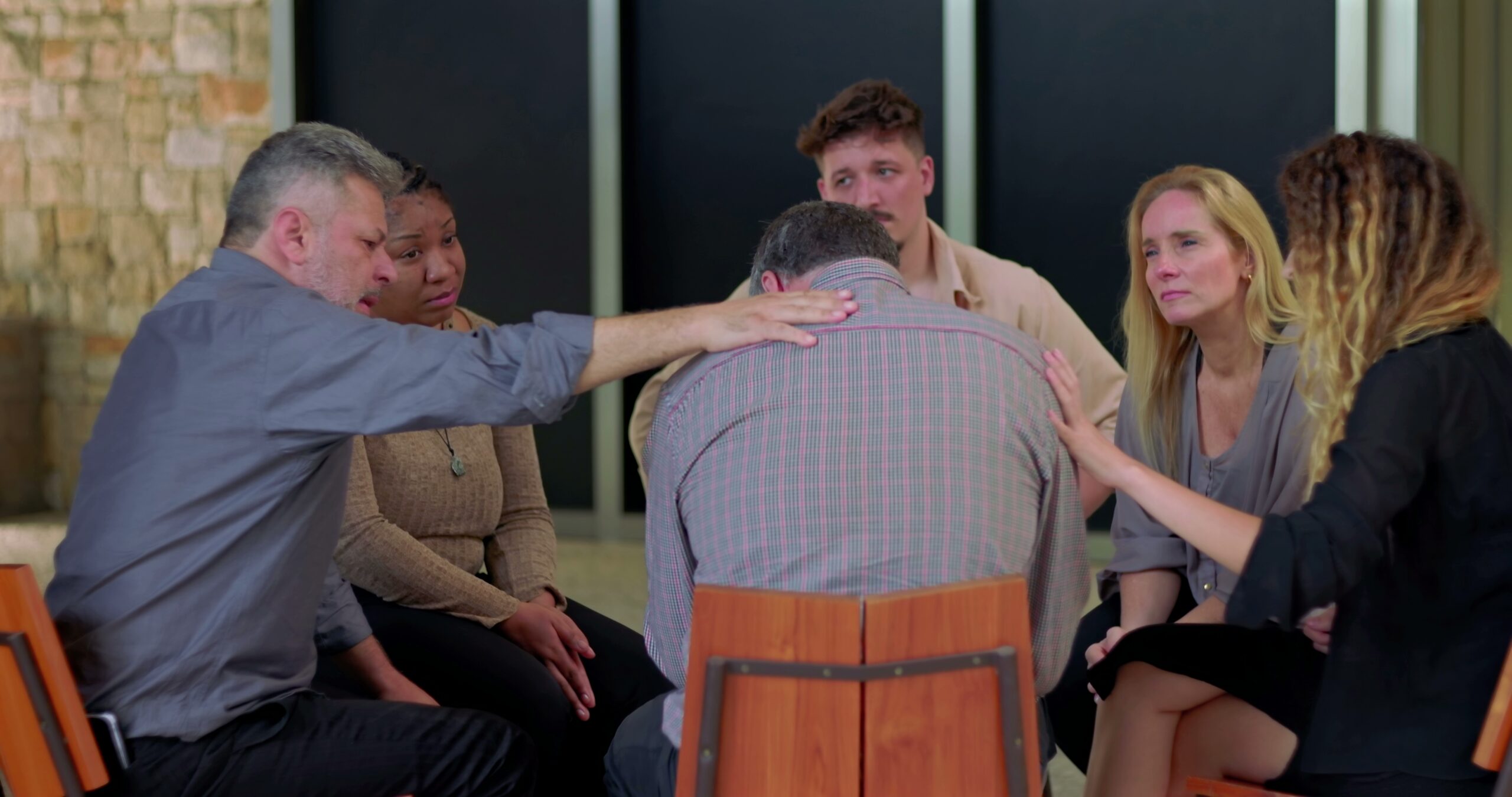 Group of people in a DBT therapy group consoling a man.