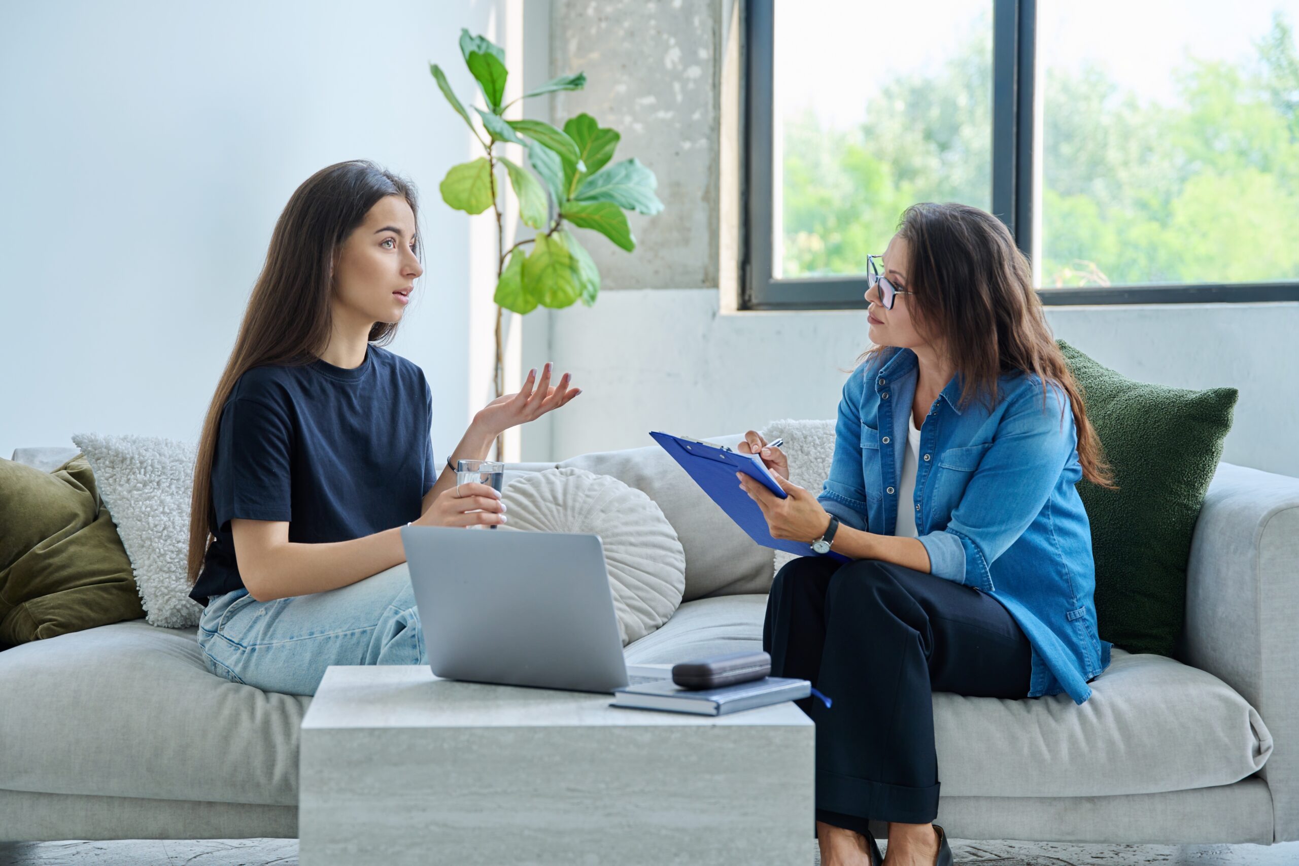 two women talking on a couch in therapy session.